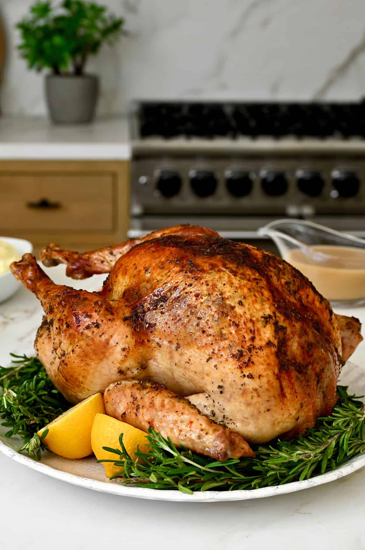 Perfect roasted turkey on a platter atop fresh herbs. 