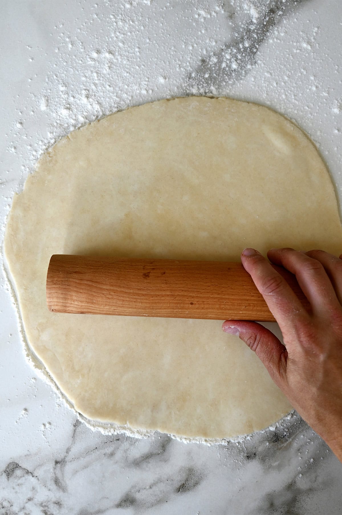 Rolling out pie dough on a floured surface.