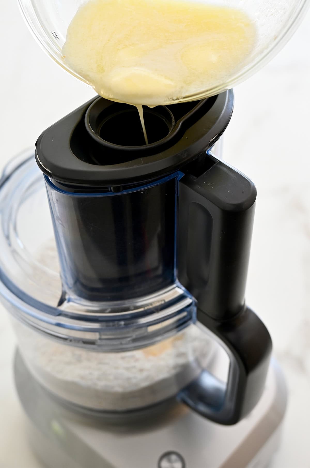 Streaming melted butter into a food processor to form homemade cheese cracker dough.