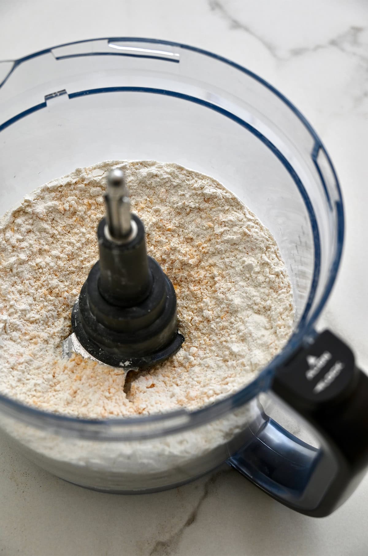 Using a food processor to pulse together cheddar cheese, flour, baking powder and salt.