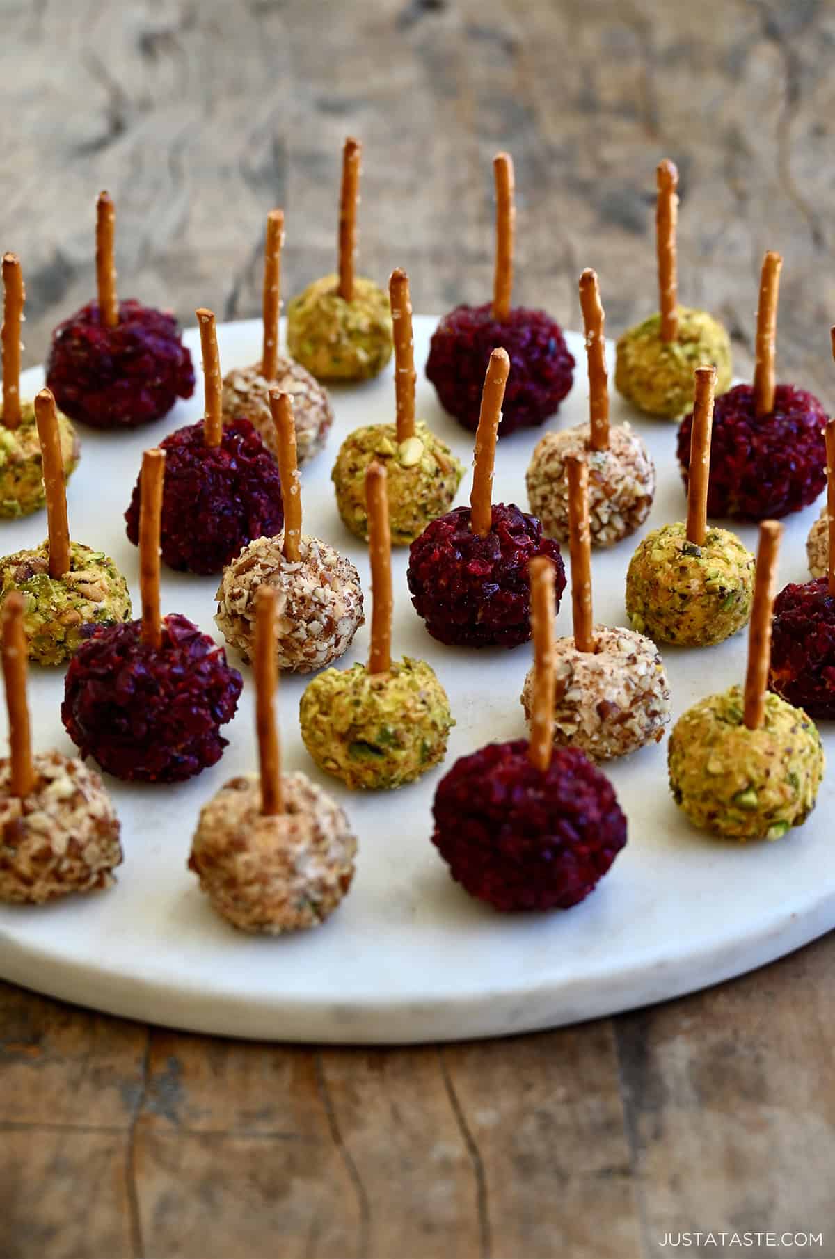 Mini cheese balls with pretzel sticks on a serving platter.