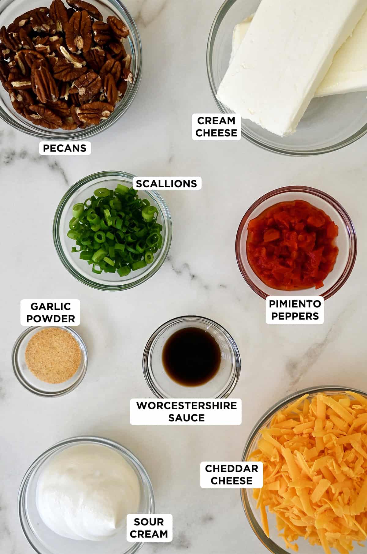 Cheese ball ingredients, including cream cheese, cheddar cheese, pimento peppers, chopped scallions, garlic powder, Worcestershire sauce, sour cream and crushed pecans.