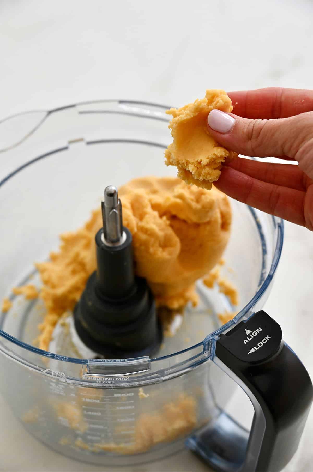 Cheese cracker dough coming together in a food processor bowl.