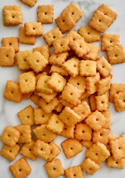 Homemade Cheez-Itโstyle cheese crackers on a marble countertop.