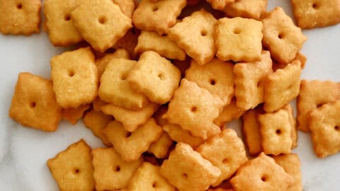 Homemade Cheez-It–style cheese crackers on a marble countertop.