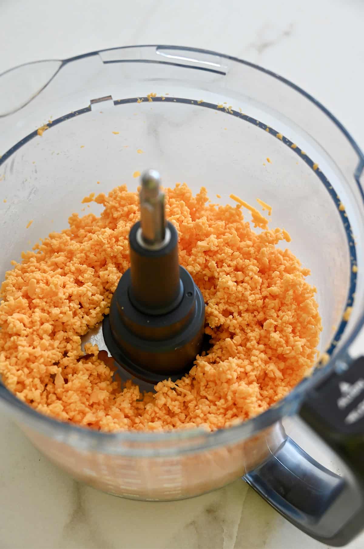 Shred cheddar cheese in a food processor.