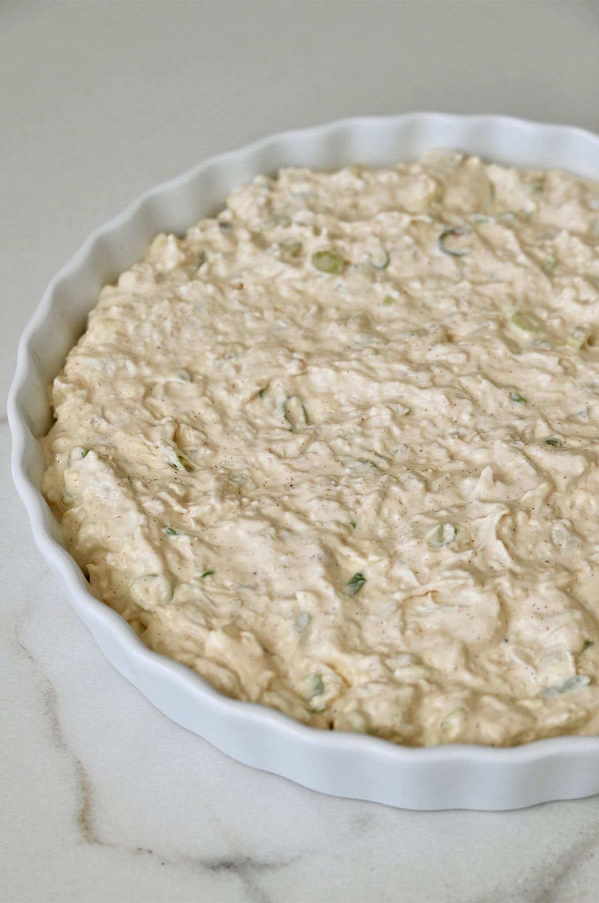 Unbaked crab dip in a shallow baking dish.