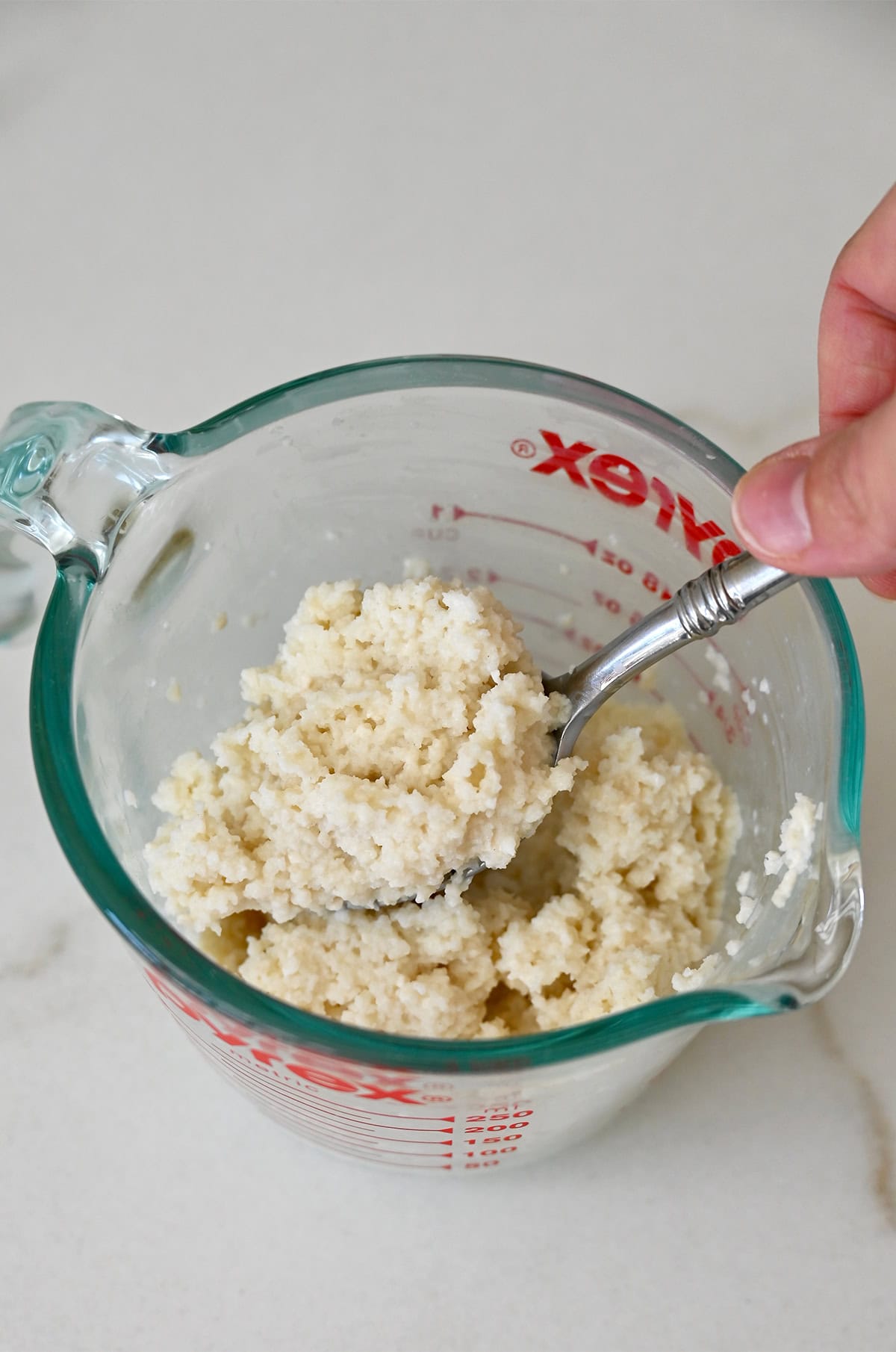 Panade (milk soaked breadcrumbs) in a glass measuring cup.