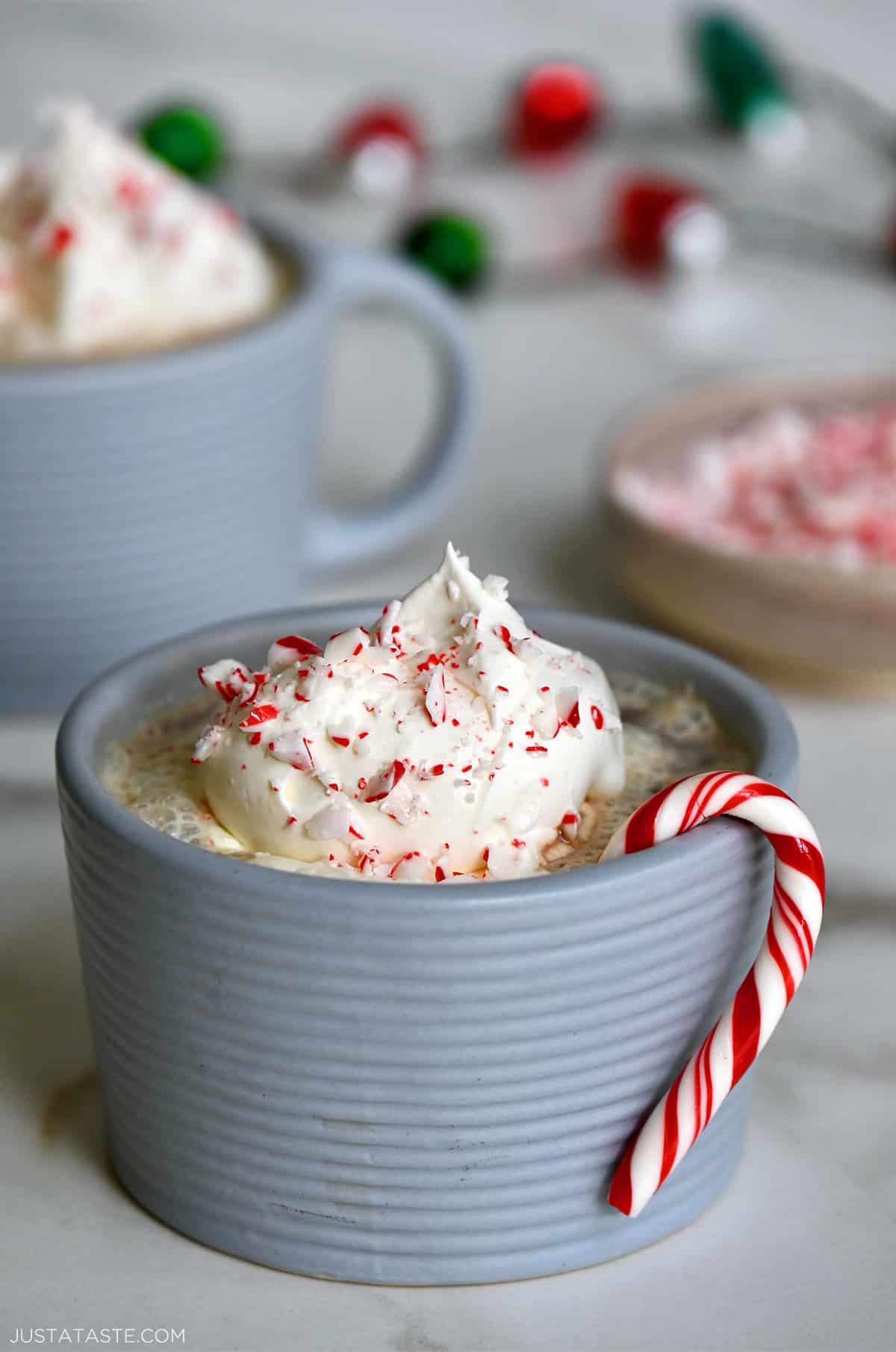 Homemade peppermint mocha in a mug with whipped cream and crushed candy canes, featuring a candy cane hanging off the side.