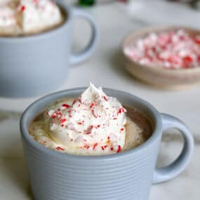 Two mugs filled with homemade peppermint mocha and topped with whipped cream.