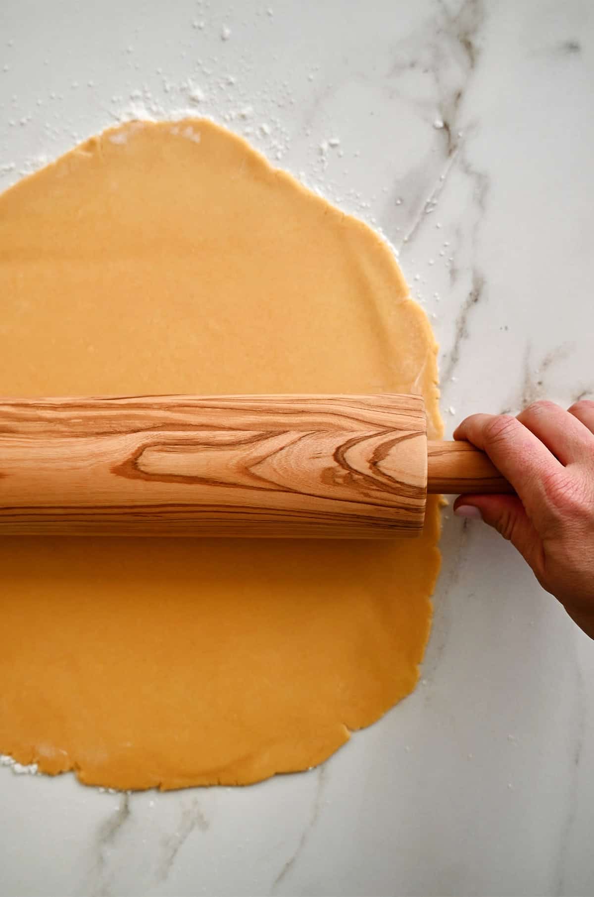 Cheddar cheese cracker dough being rolled into a thin sheet.