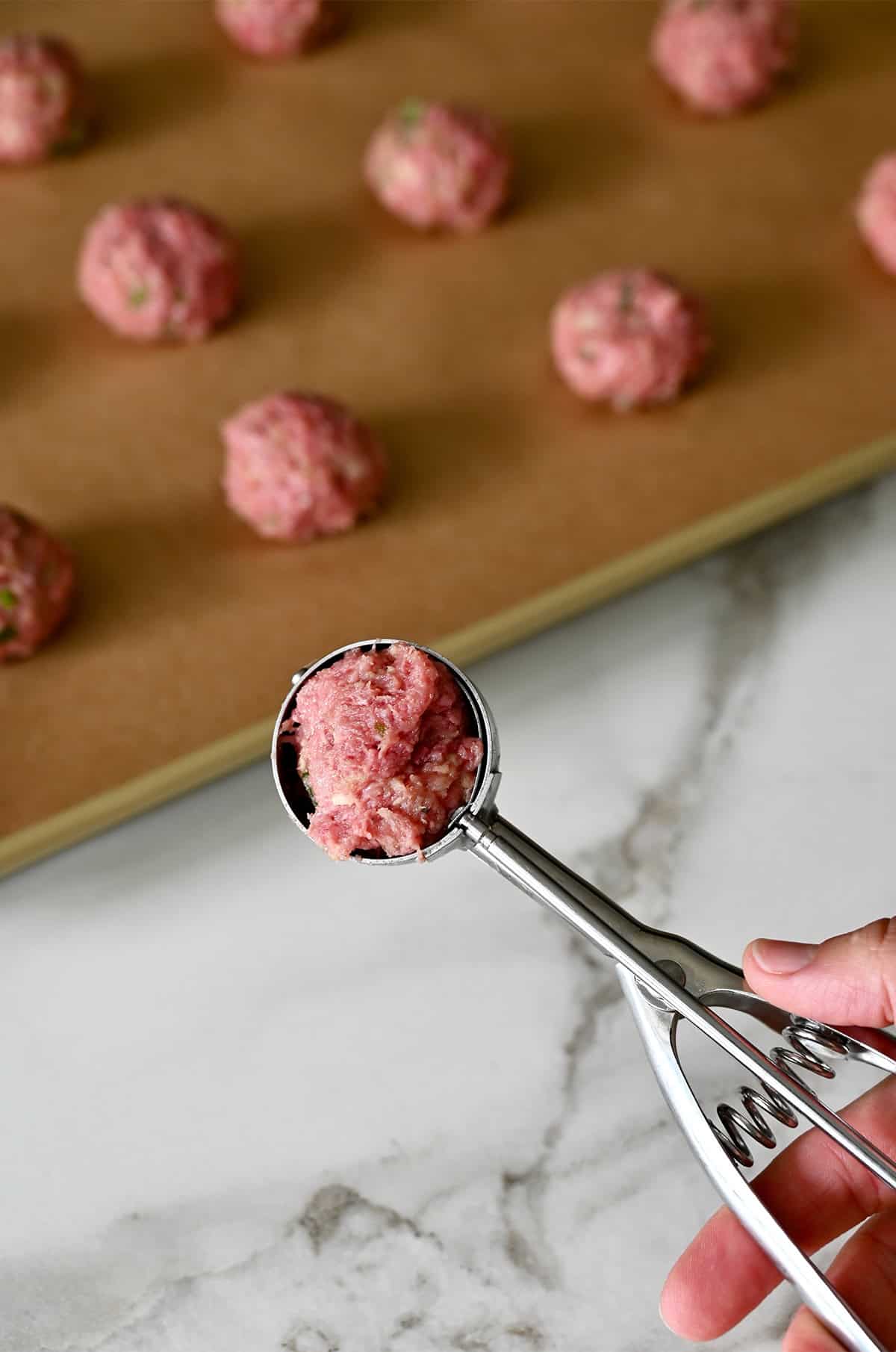 Using a small cookie scoop to make cocktail-sized meatballs.