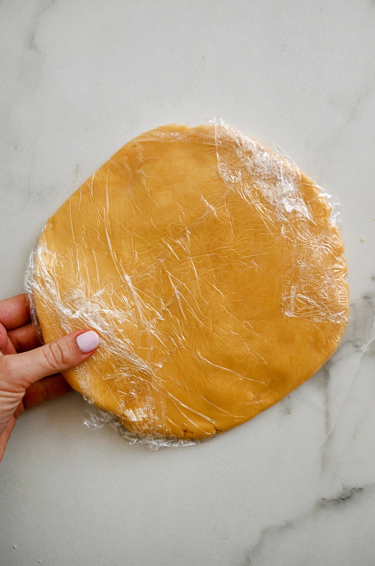 Chilled homemade cheese cracker dough wrapped in plastic wrap.