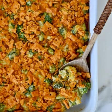 Broccoli cheese casserole topped with cheese crackers in a white casserole dish.