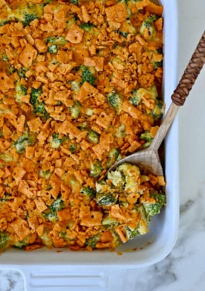 Broccoli cheese casserole topped with cheese crackers in a white casserole dish.