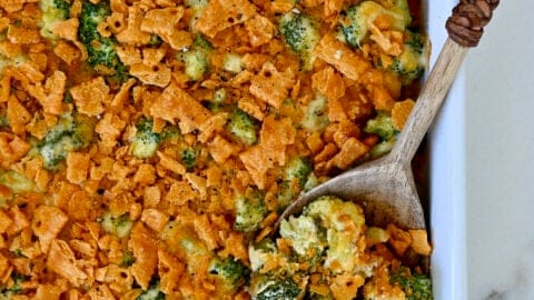 Broccoli cheese casserole topped with cheese crackers in a white casserole dish.