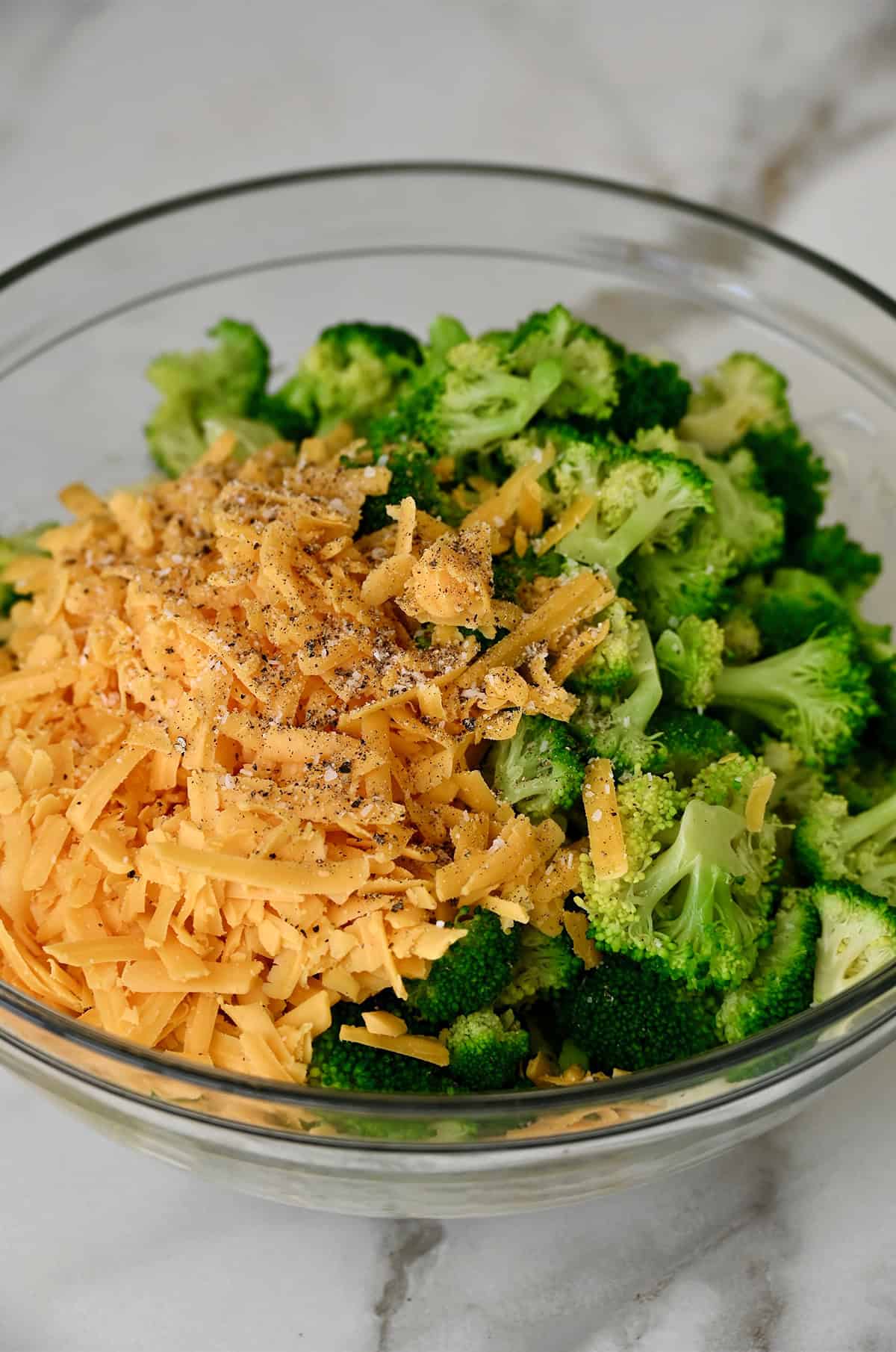 Broccoli florets and cheddar cheese atop cream of mushroom soup in a bowl.