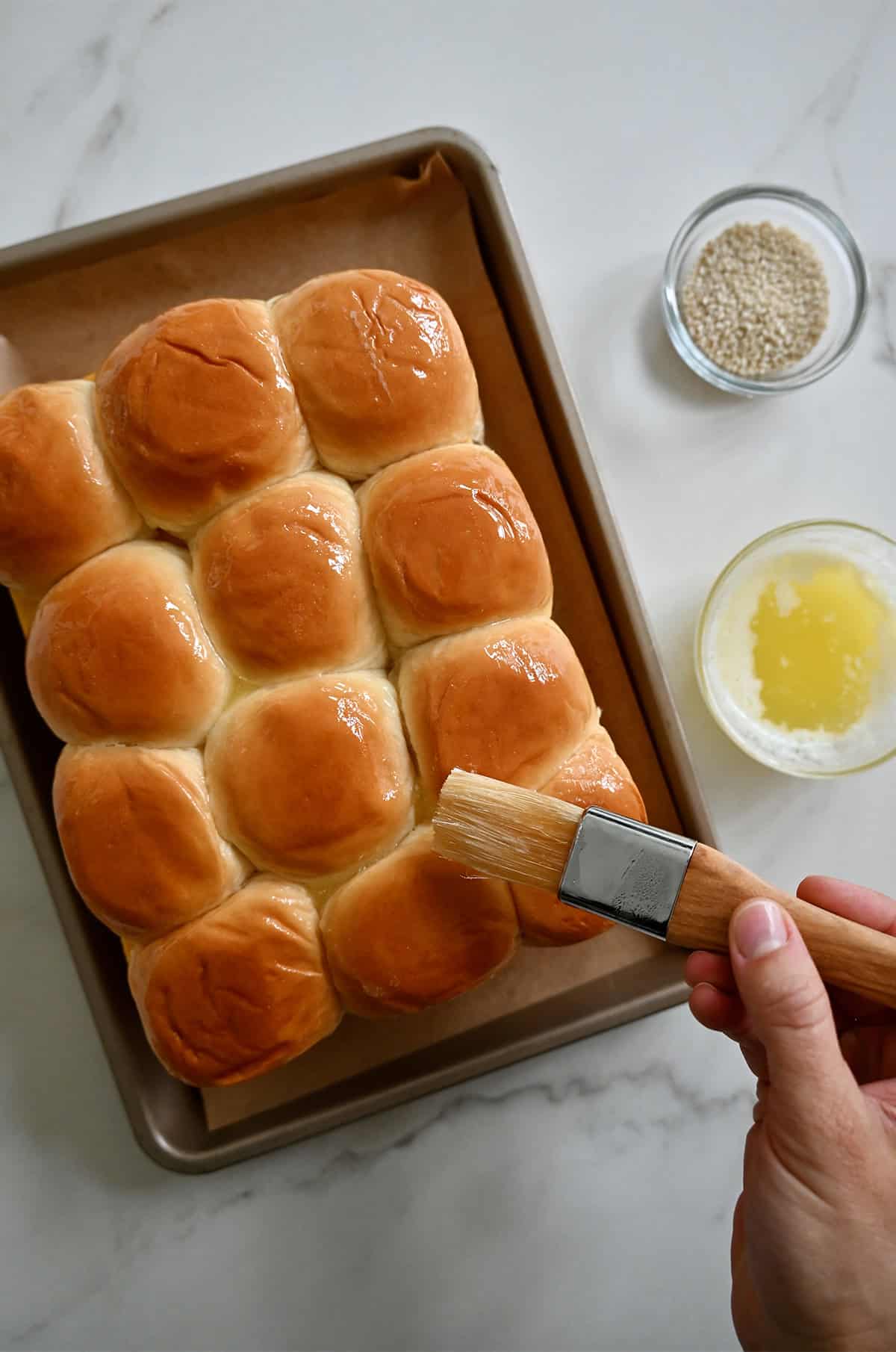 Brushing the tops of the rolls with melted butter.