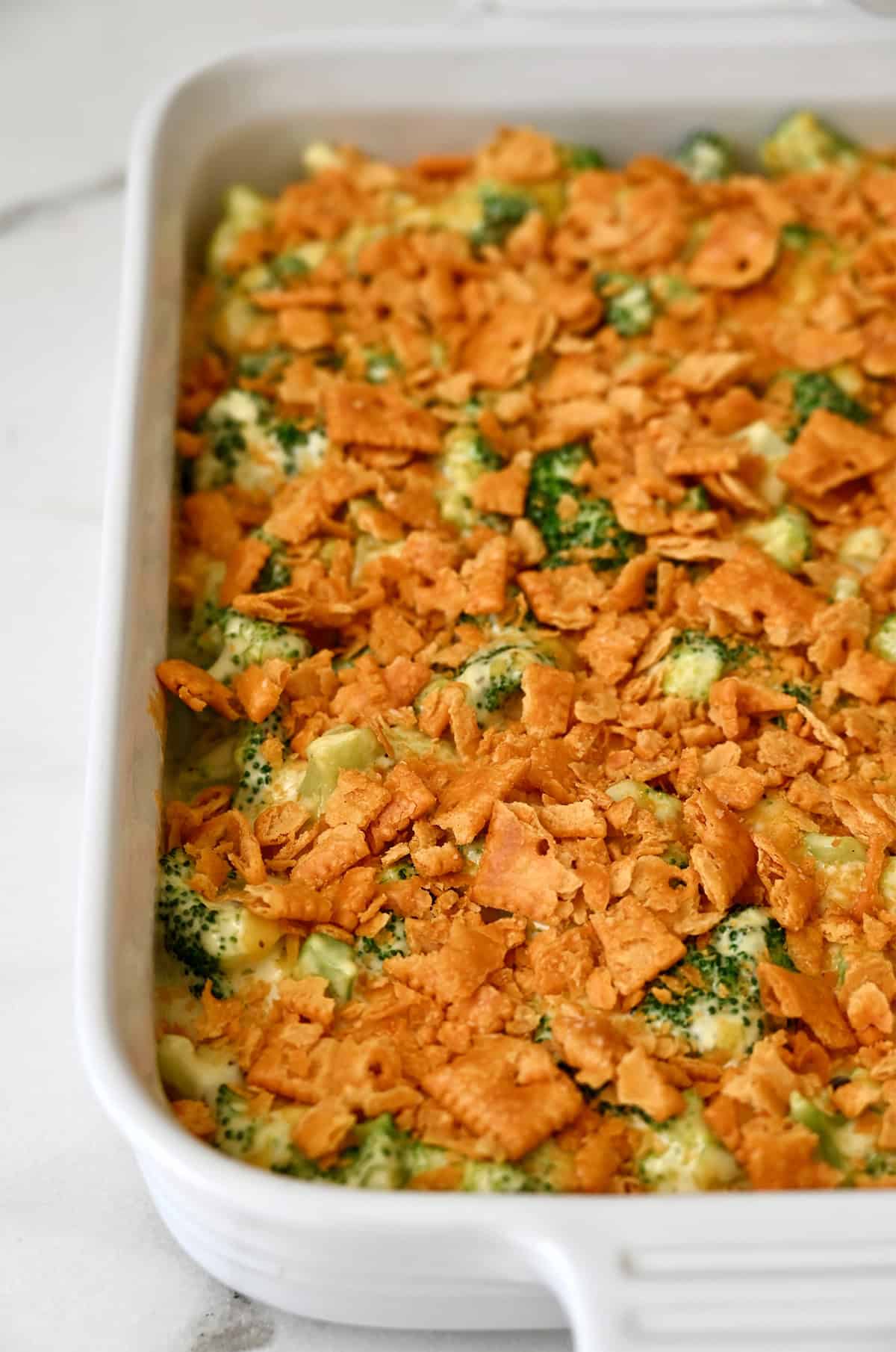 Baked broccoli casserole with cheese and a layer of crushed crackers in a baking dish.