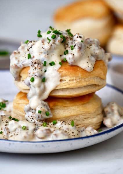 Homemade sausage gravy spooned over two flake biscuits piled atop each other.