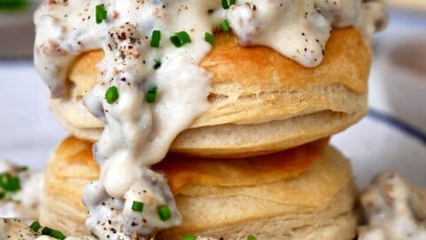 Homemade sausage gravy spooned over two flake biscuits piled atop each other.