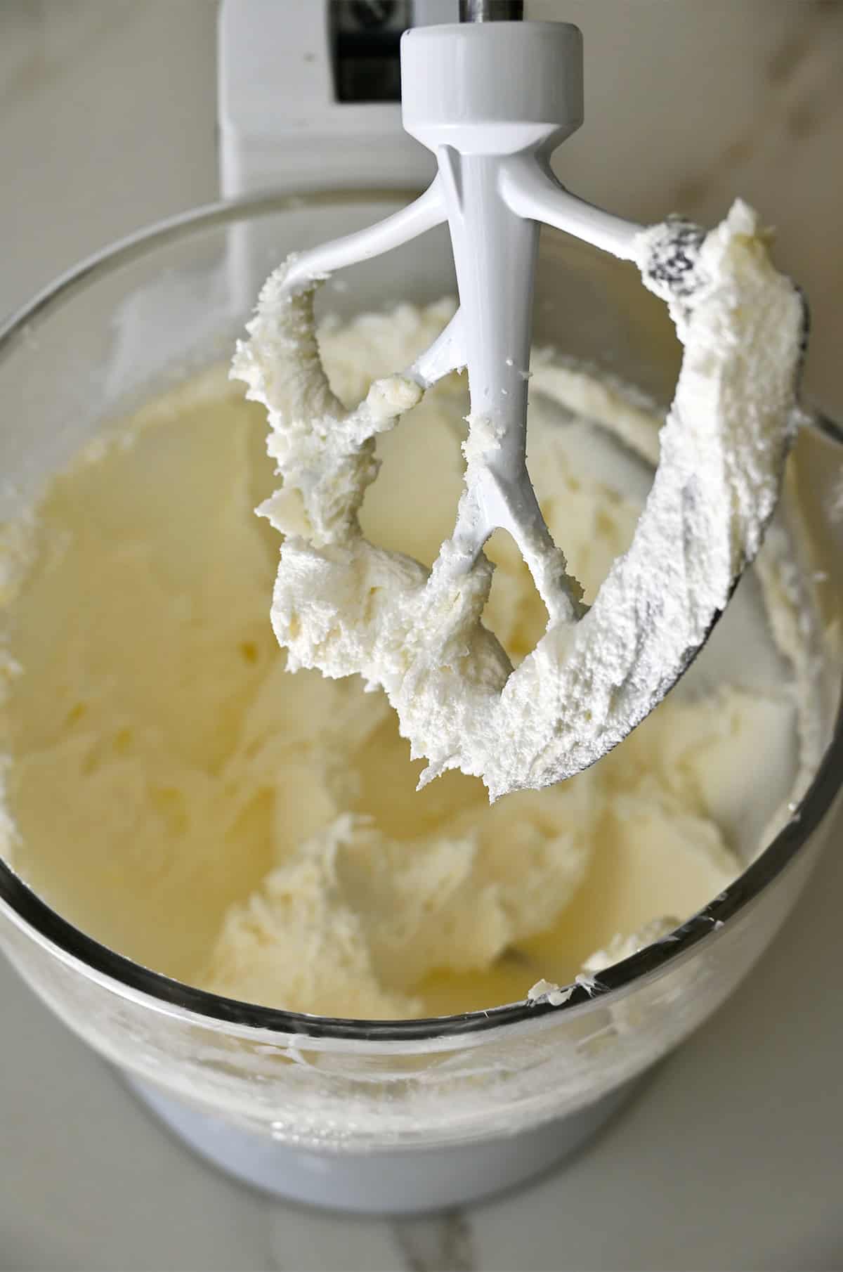 Whipped butter covering the paddle attachment of a stand mixer.