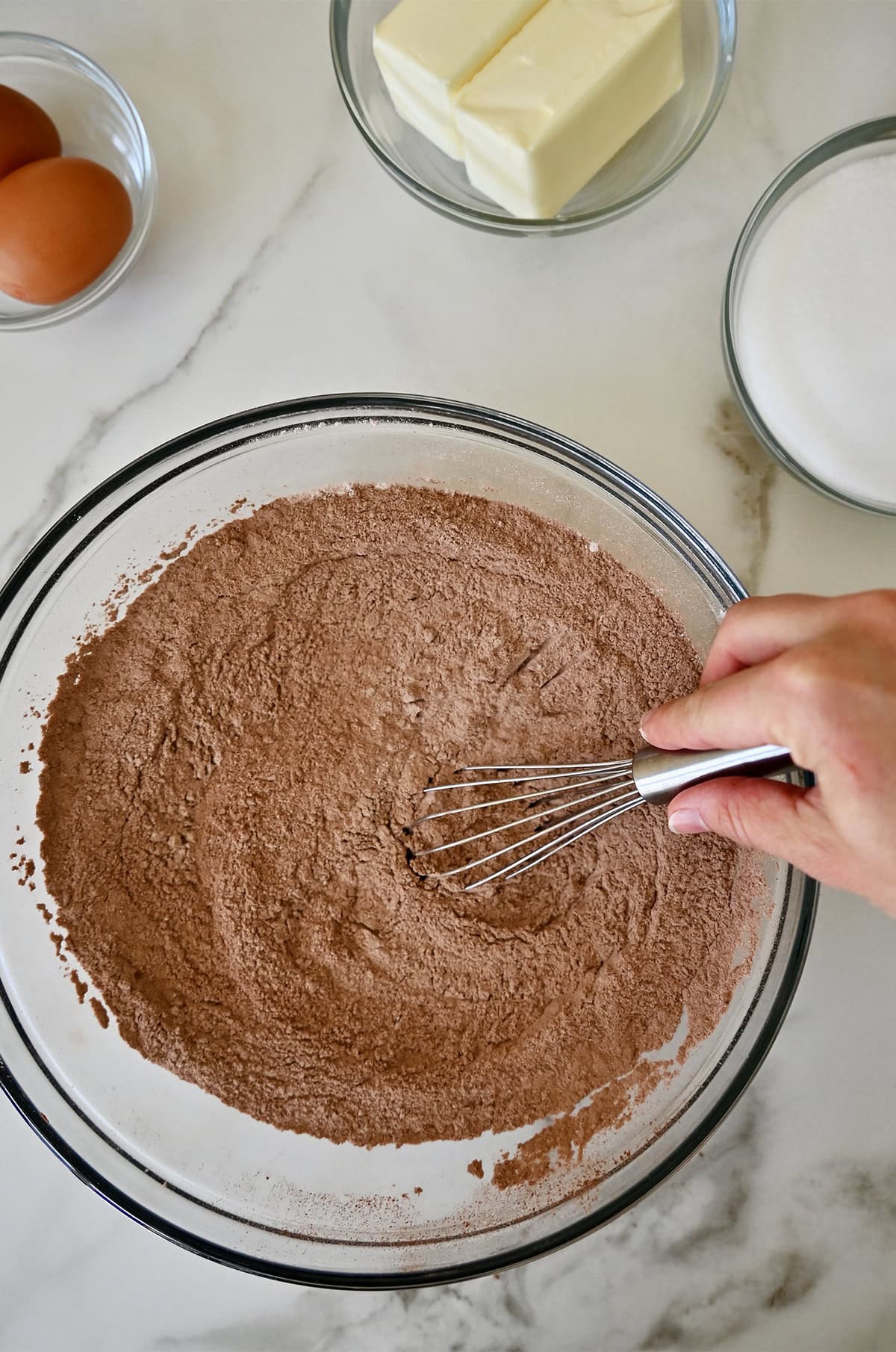 Whisking together flour and cocoa powder in a bowl.