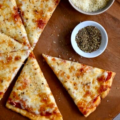Slices of golden brown cottage cheese pizza crust topped with pizza sauce and cheese on a wood platter.