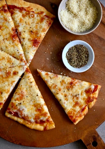 Slices of golden brown cottage cheese pizza crust topped with pizza sauce and cheese on a wood platter.