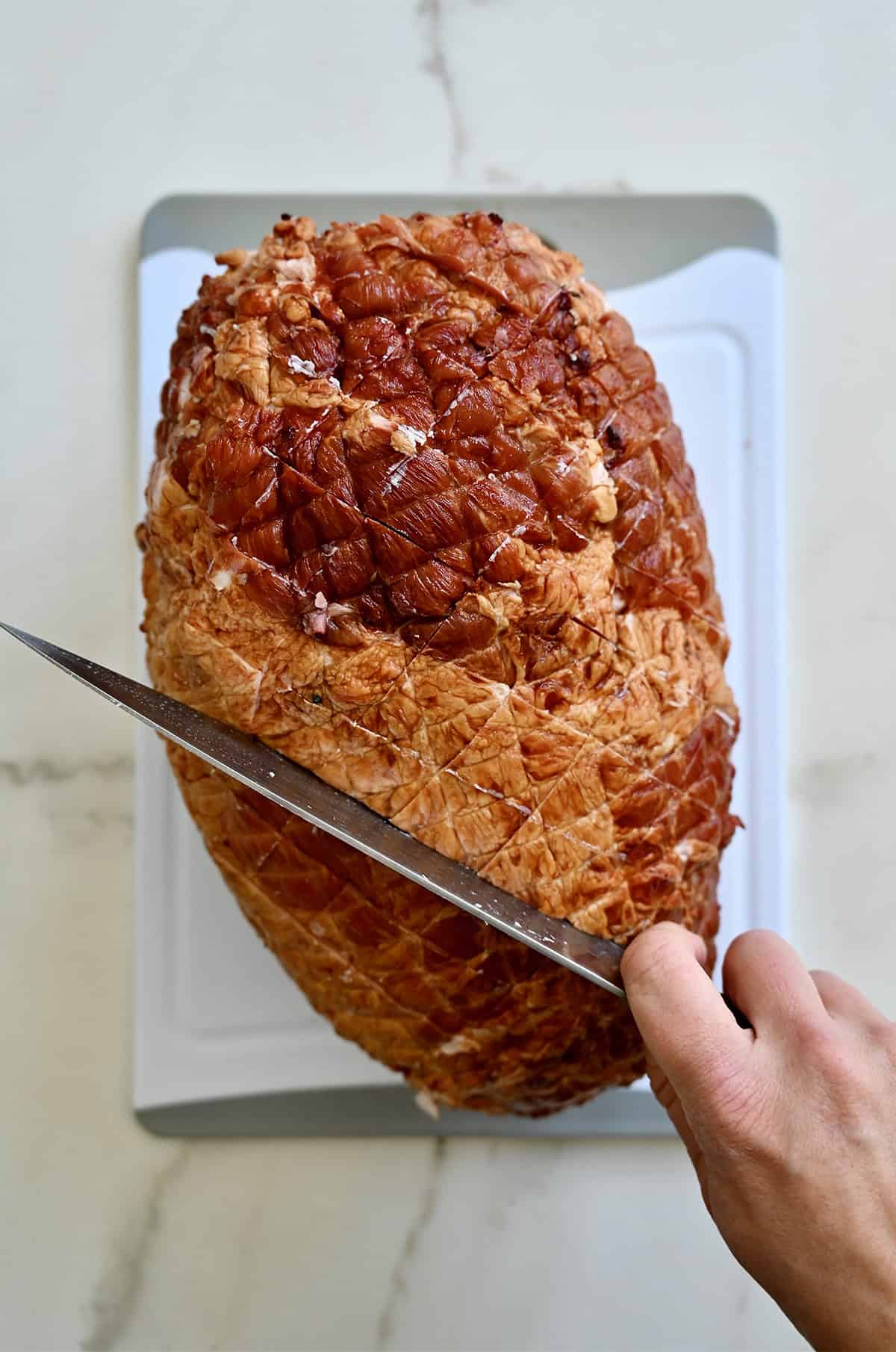 Aštriu peiliu įmušdamas kumpį su kryžminio kroso raštu.