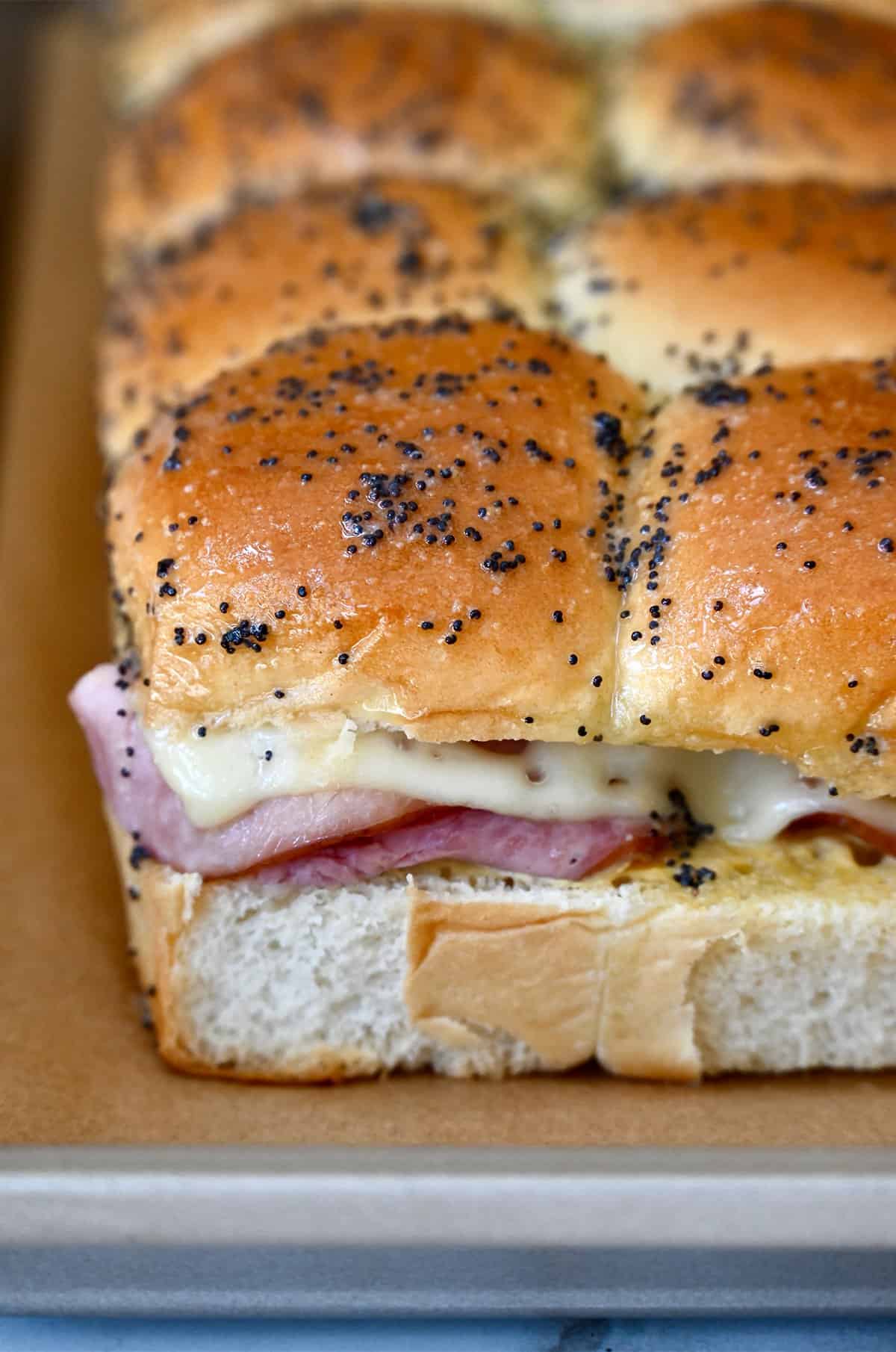 Baked ham and Swiss cheese sliders with a poppy seed butter topping.