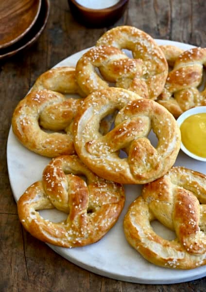 Cottage cheese soft pretzels on a plate with a small ramekin containing yellow mustard.
