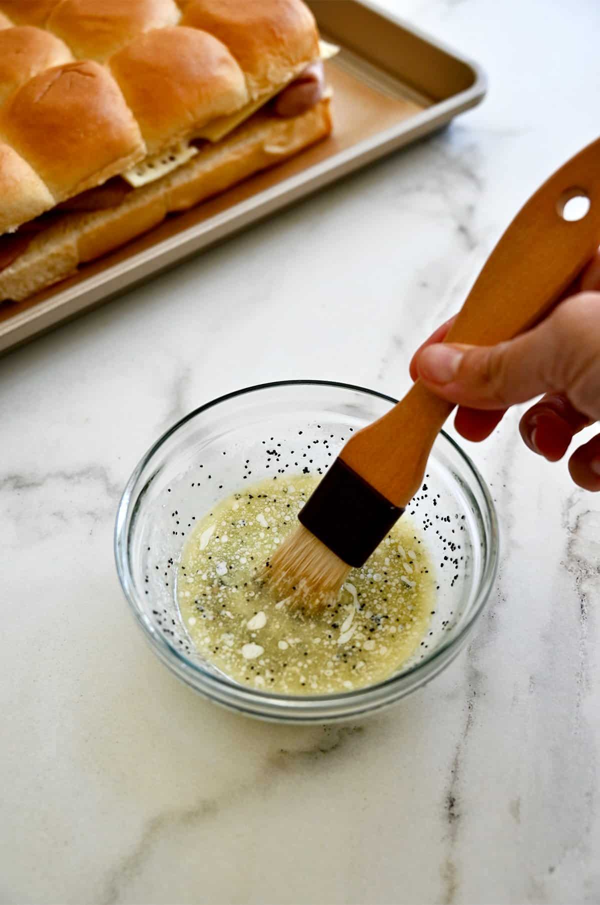 A small bowl containing garlic butter sauce with poppy seeds.