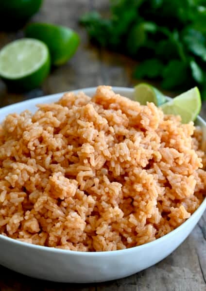 Mexican rice in a serving bowl with two lime wedges.