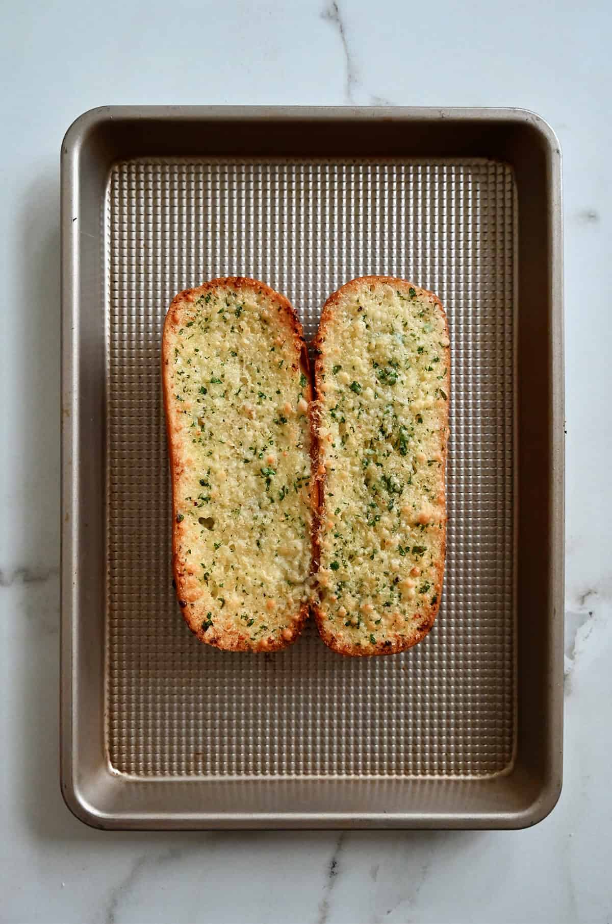 Toasted garlic butter bun on a baking sheet.