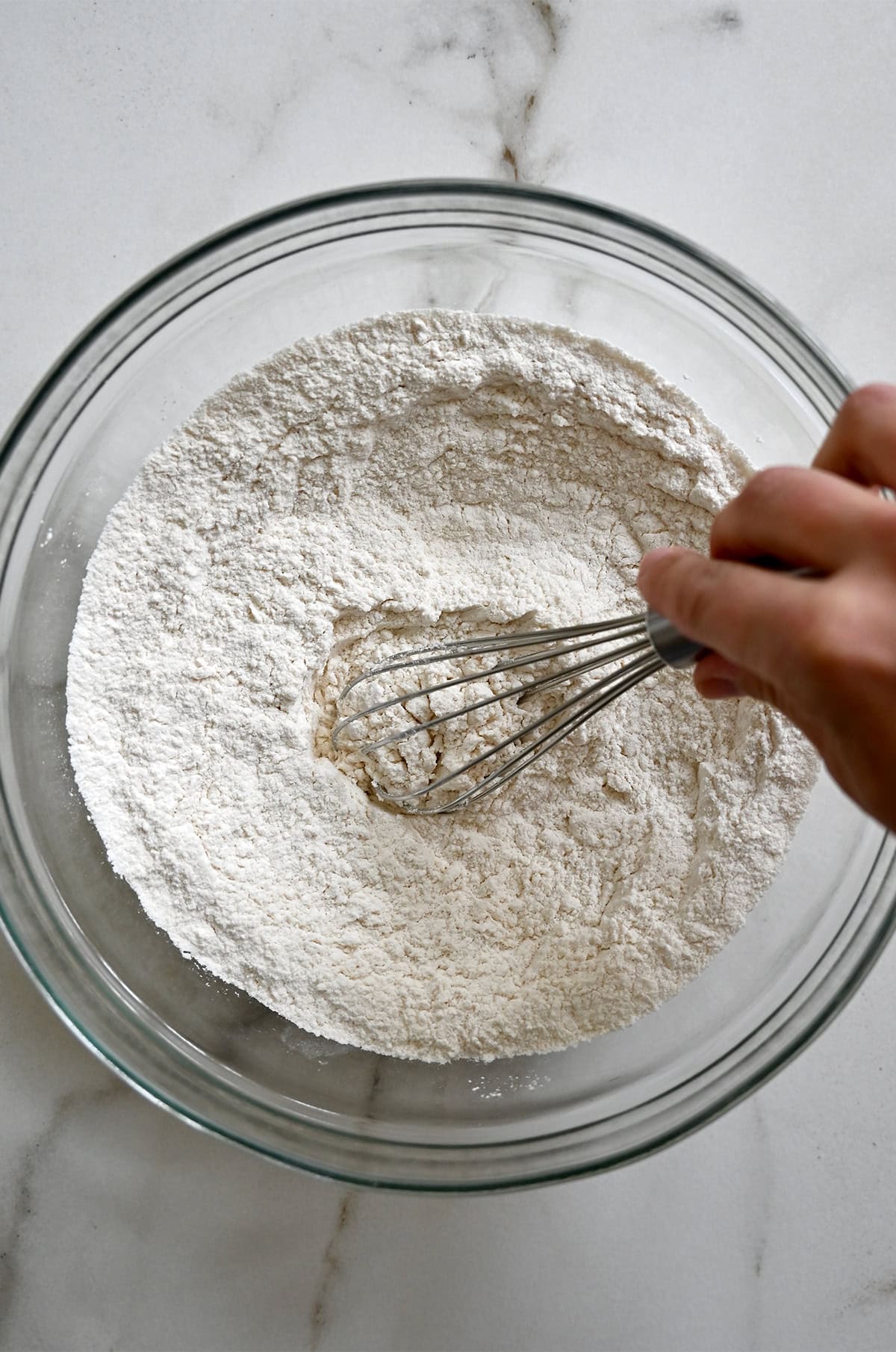 Flour, baking powder and salt being whisked together in a large bowl.