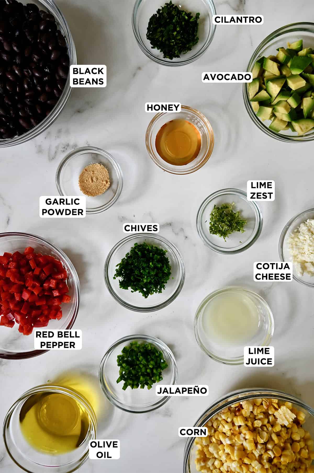 Black bean corn salad ingredients in various sizes of glass bowls.