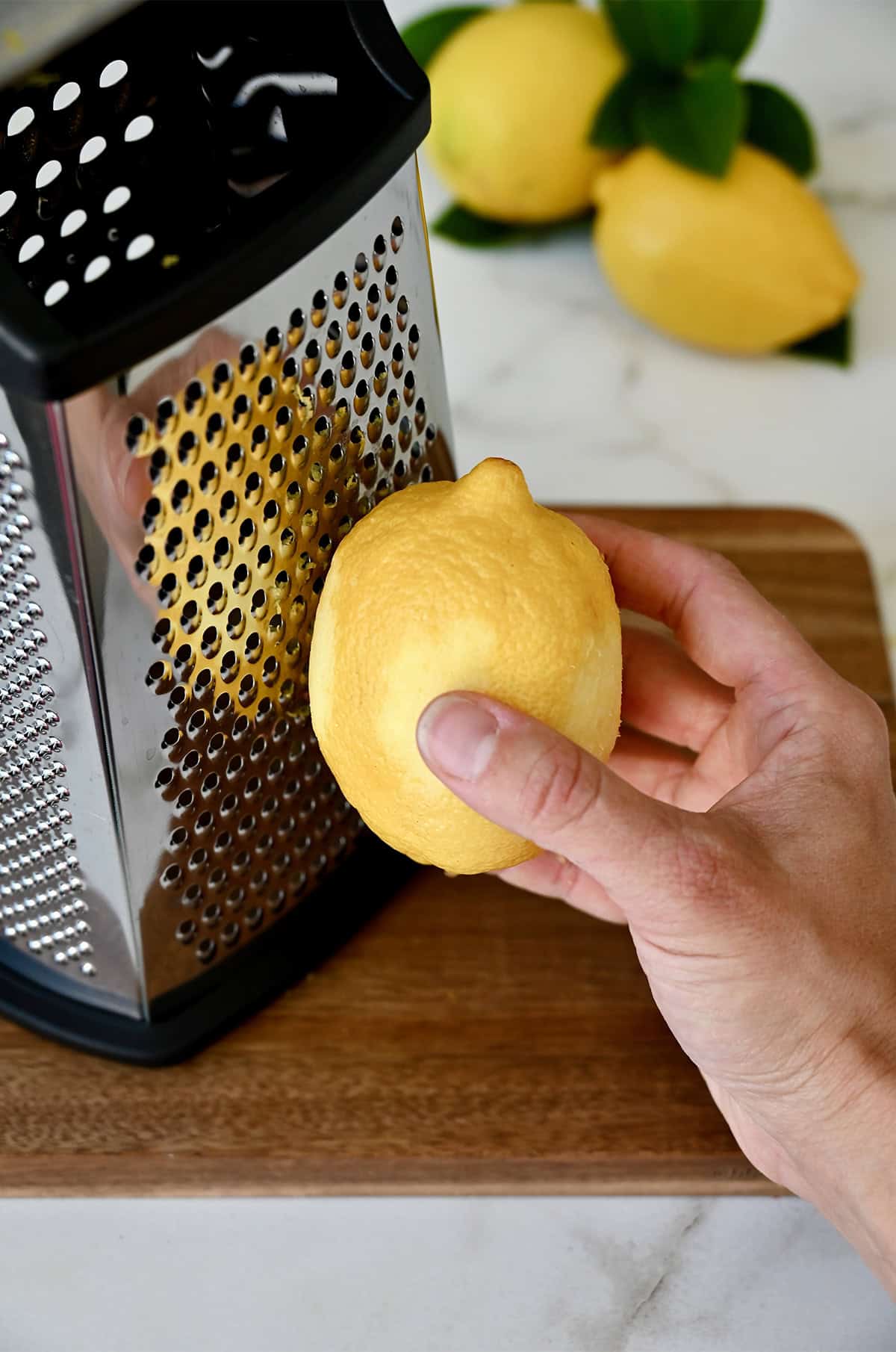 Zesting a lemon on the small holes of a box grater.