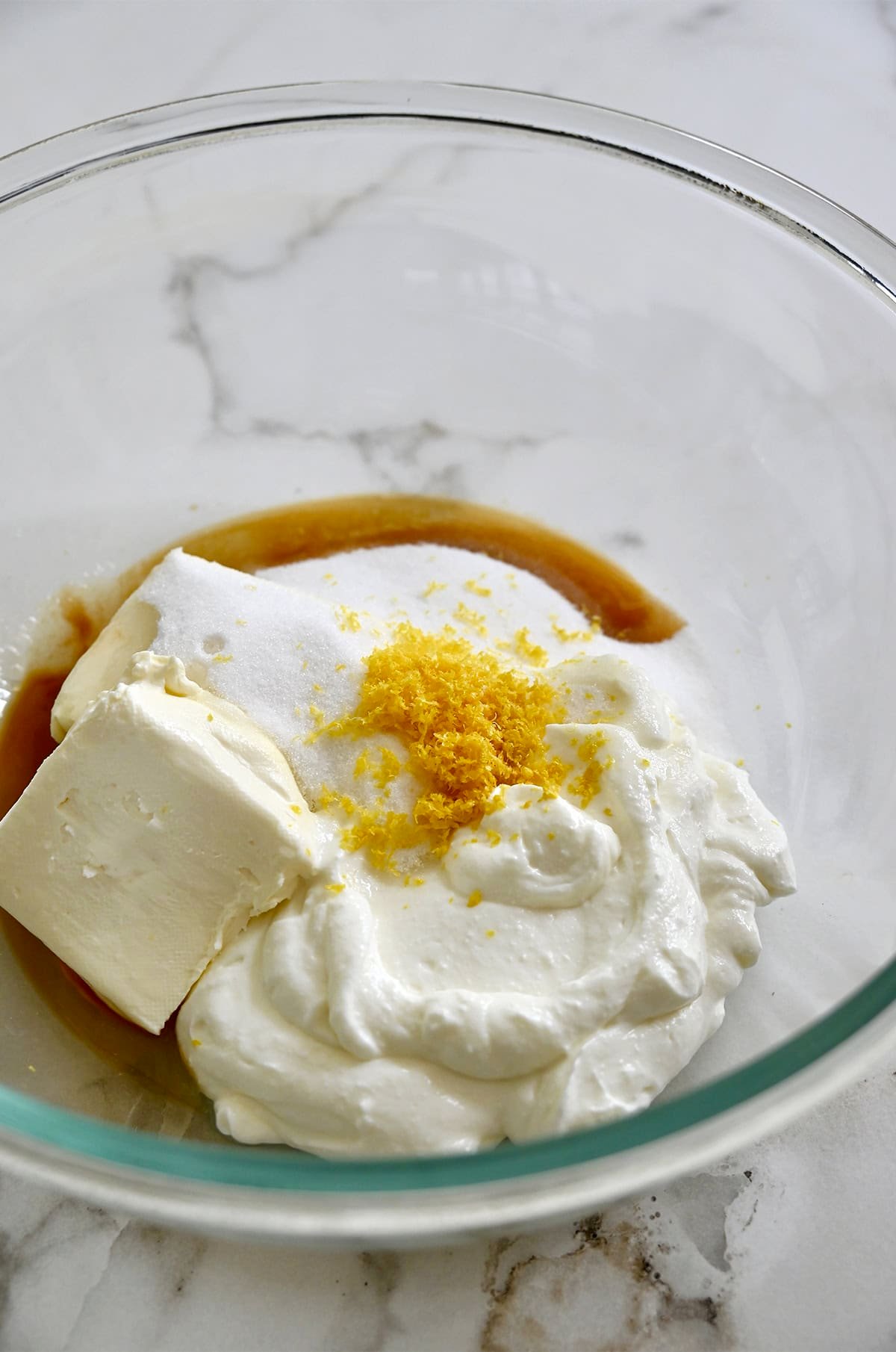 Whipped cottage cheese, cream cheese, sugar, vanilla extract, lemon juice and lemon zest in a glass bowl.