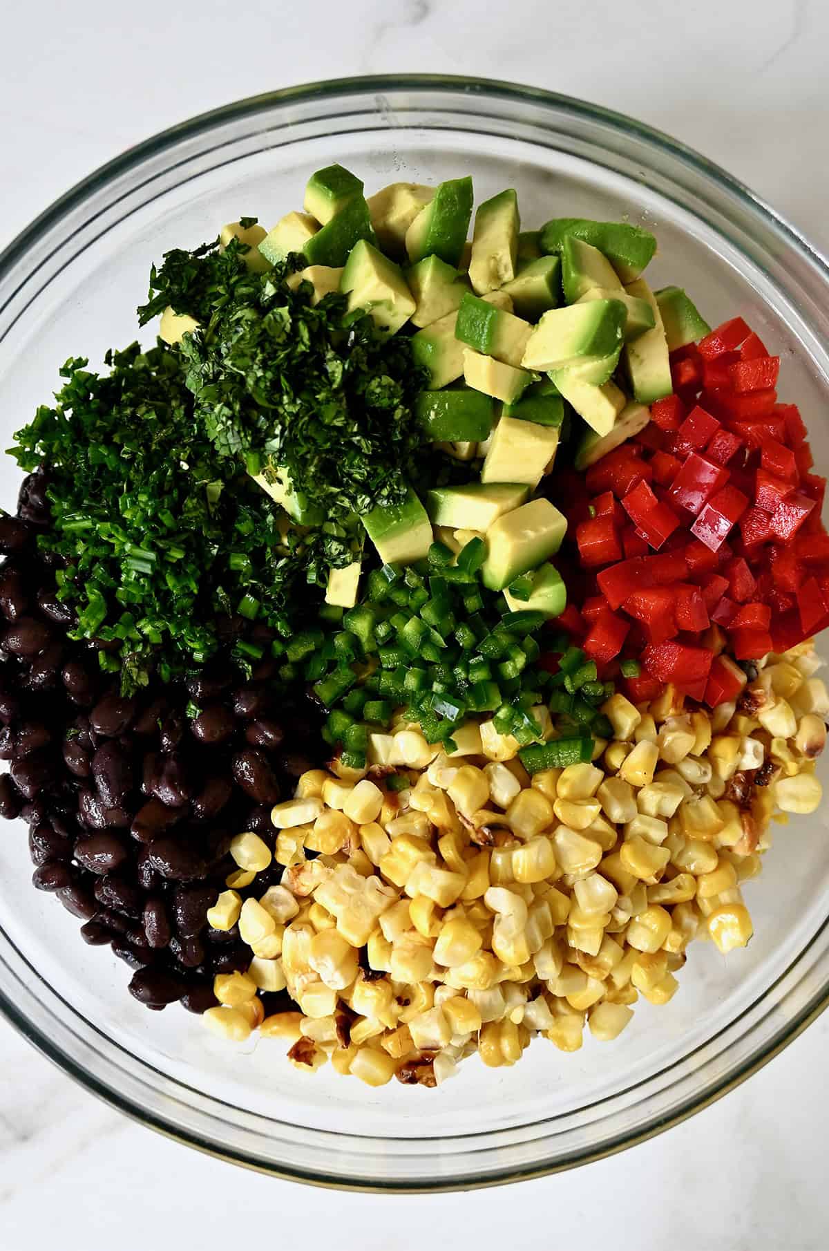 Black beans, chopped cilantro, corn, diced avocado, diced red bell pepper, chopped fresh chives and diced jalapeño in a large bowl.