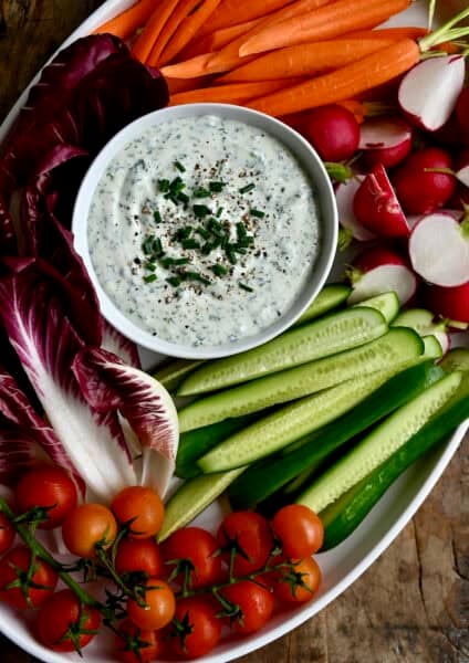 Cottage cheese veggie dip in a bowl on a platter surrounded by fresh veggies.