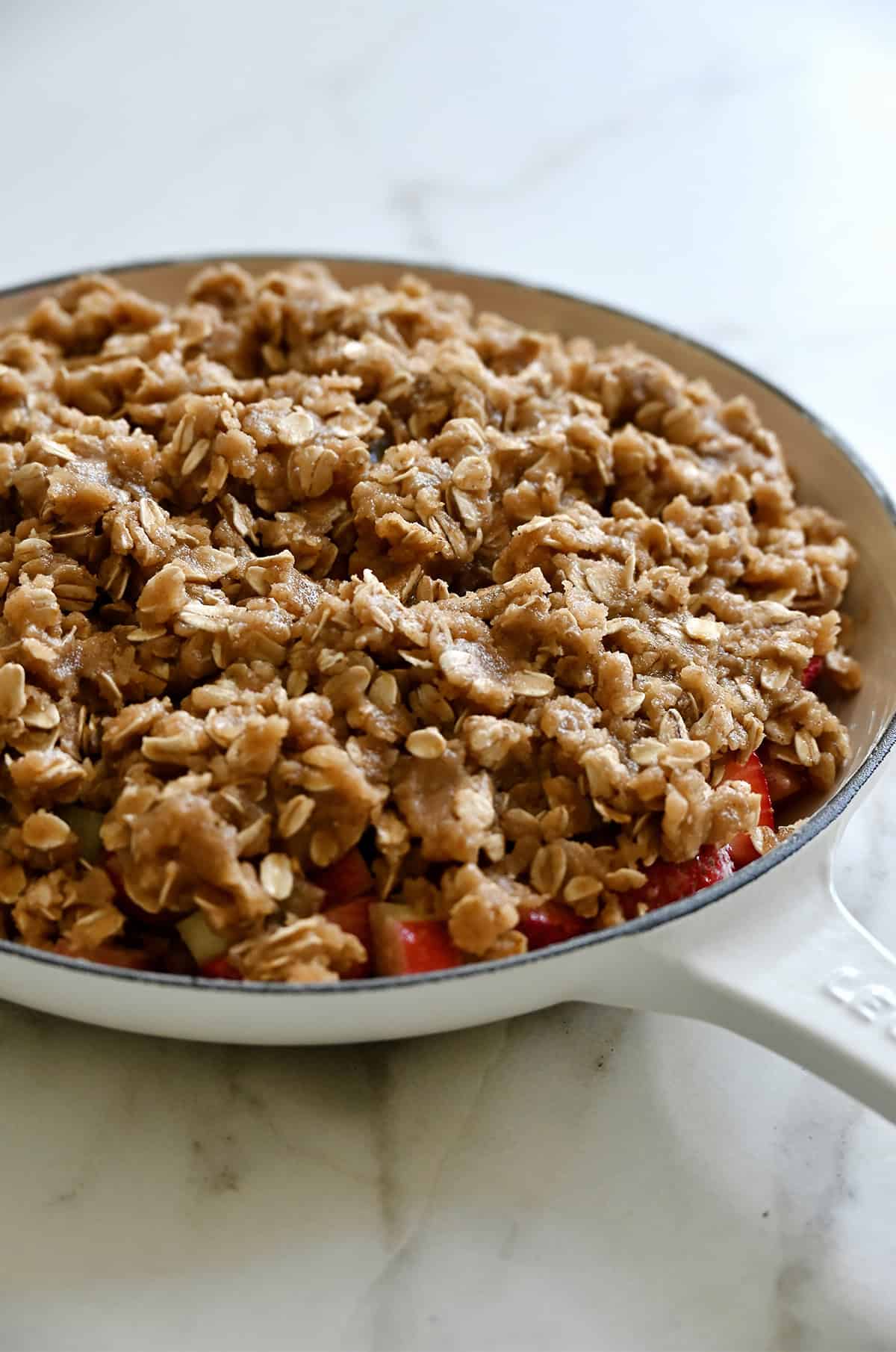An unbaked fruit crisp in an oven-safe skillet.