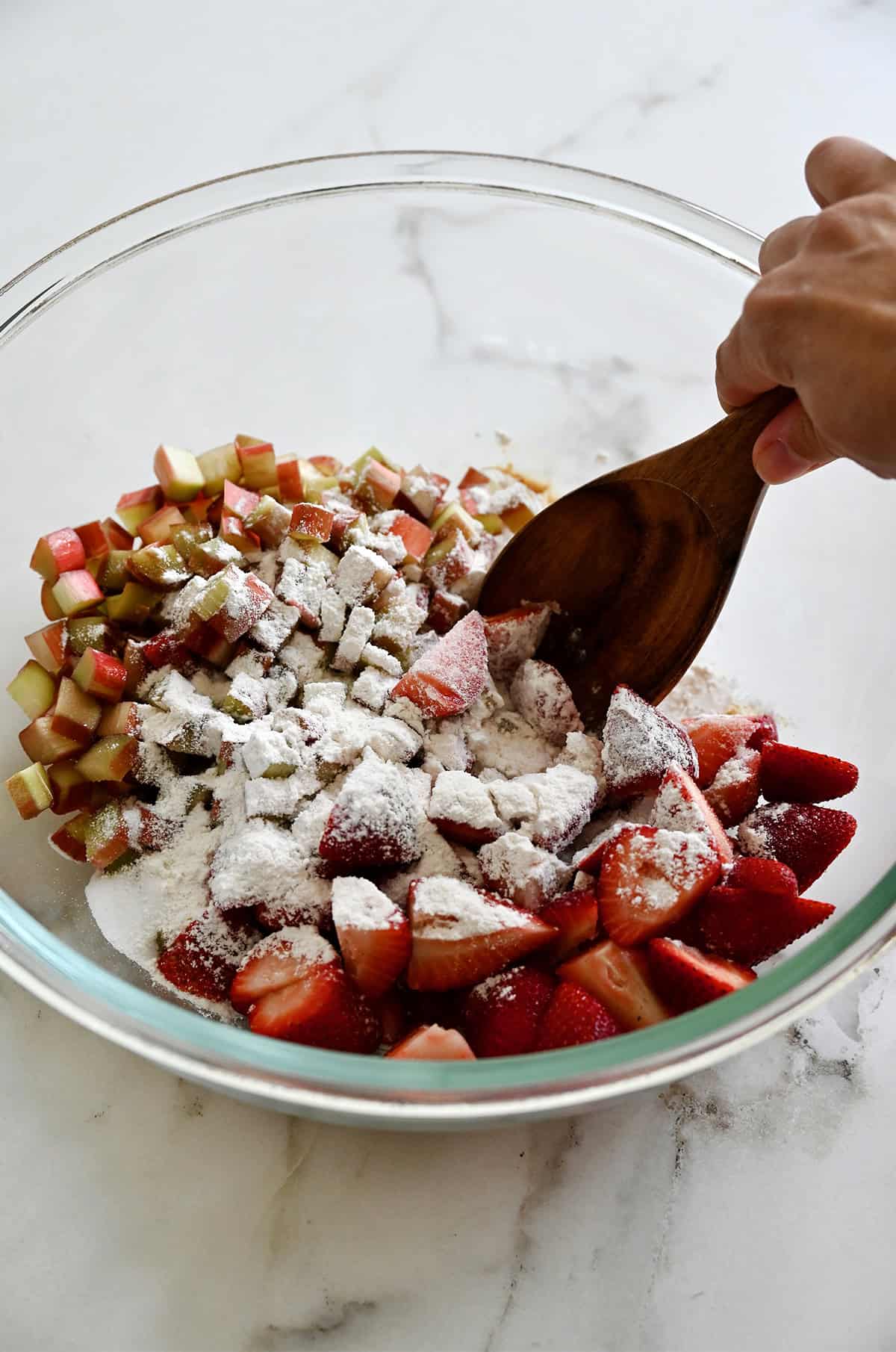Diced rhubarb and strawberries in a bowl topped with sugar.