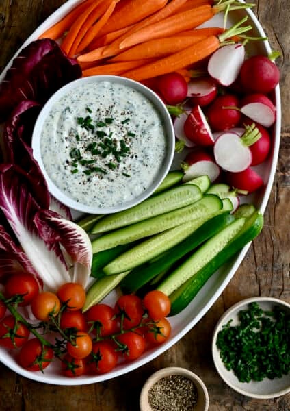 High protein cottage cheese veggie dip in a small bowl on a serving platter surrounded by fresh veggies.