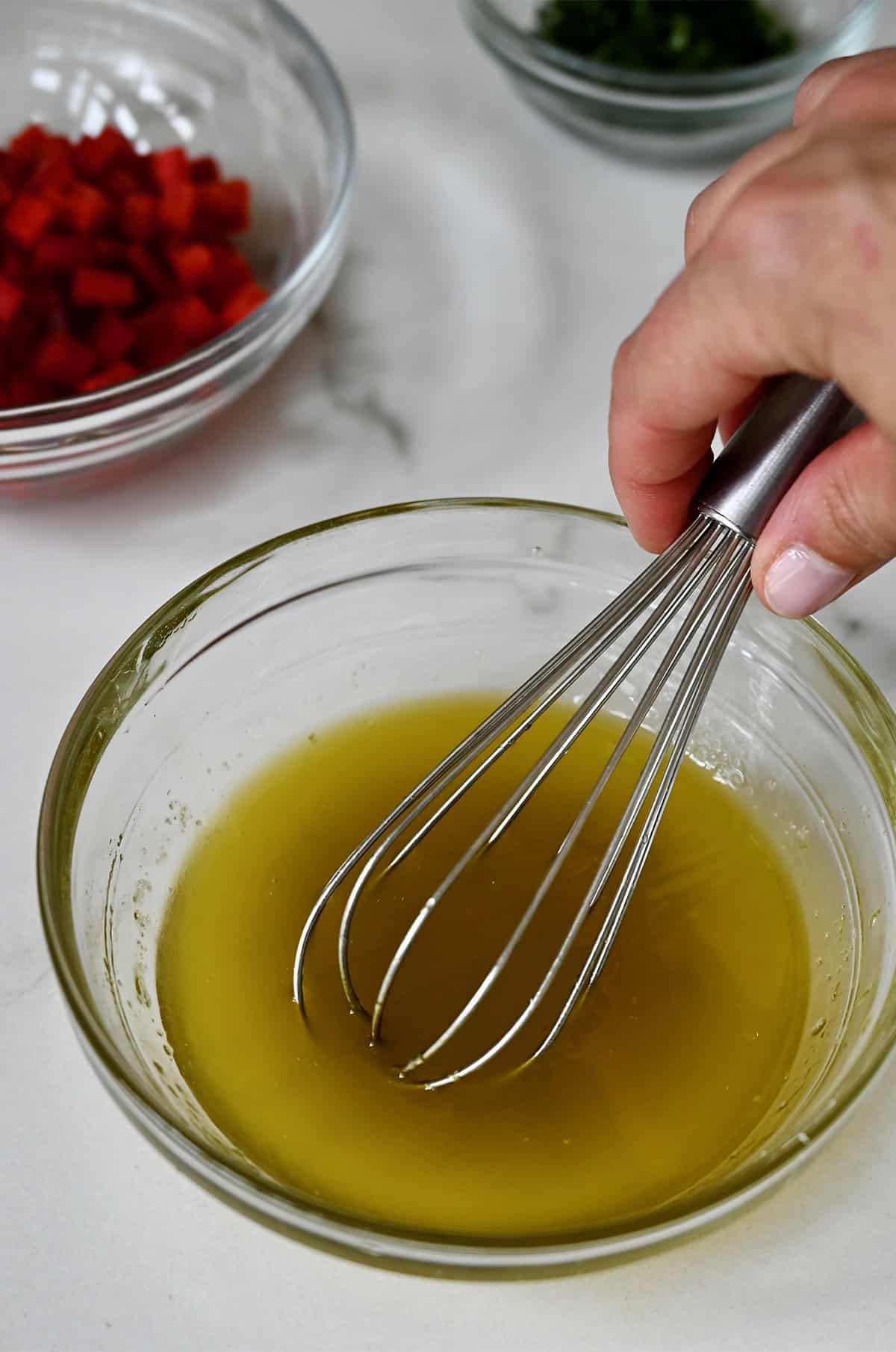 Honey lime dressing being whisked together in a small bowl.