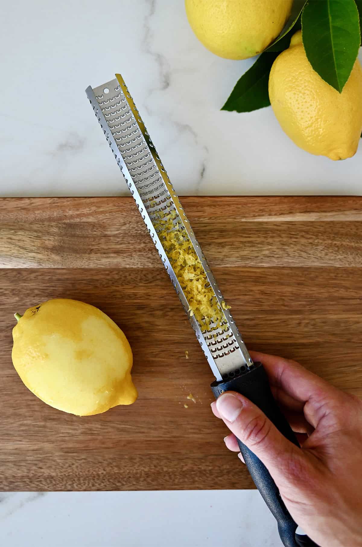 How to zest a lemon with a microplane over a cutting board.