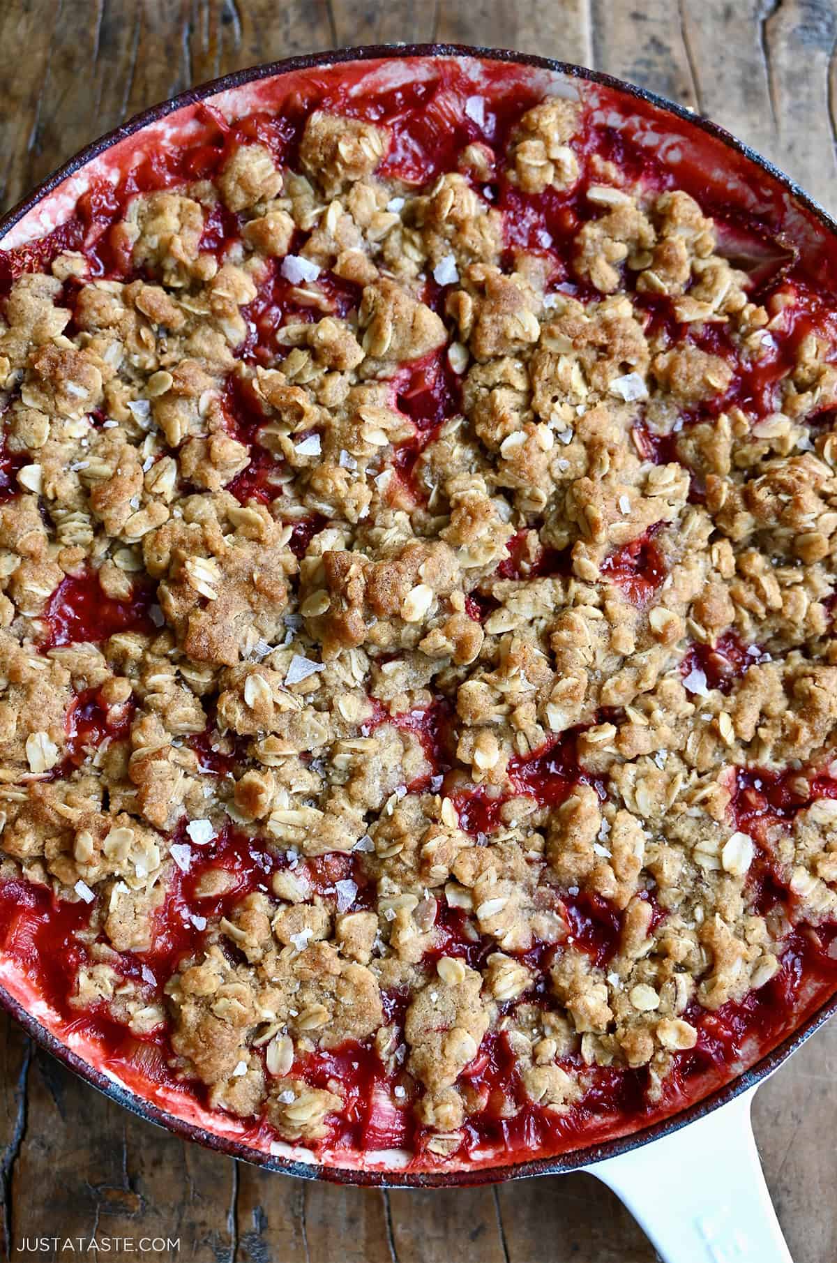 Strawberry rhubarb crisp in a skillet with a golden brown oat crumb topping.