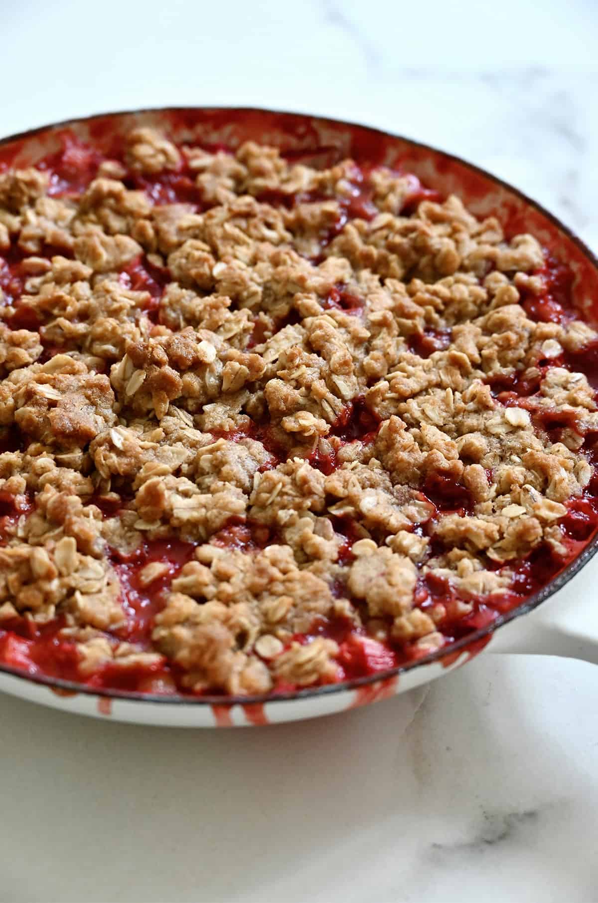 Golden brown and bubbling rhubarb strawberry crisp in a skillet.