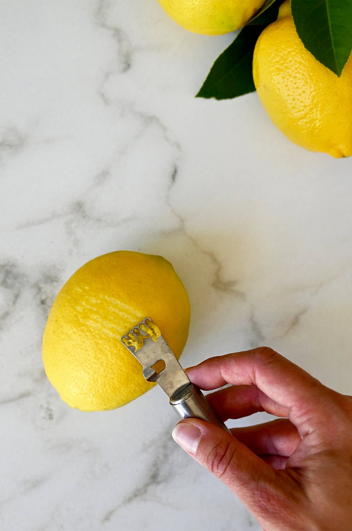 Zesting a lemon with a citrus zester.