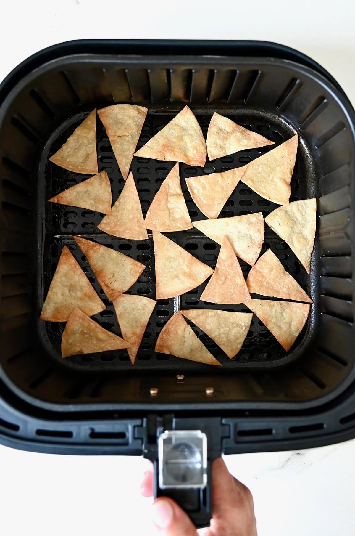 Air fryer tortilla chips in the basket of an air fryer.